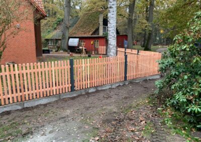 Lärchen Staketenzaun mit Stahlpfosten und Betonbordstein